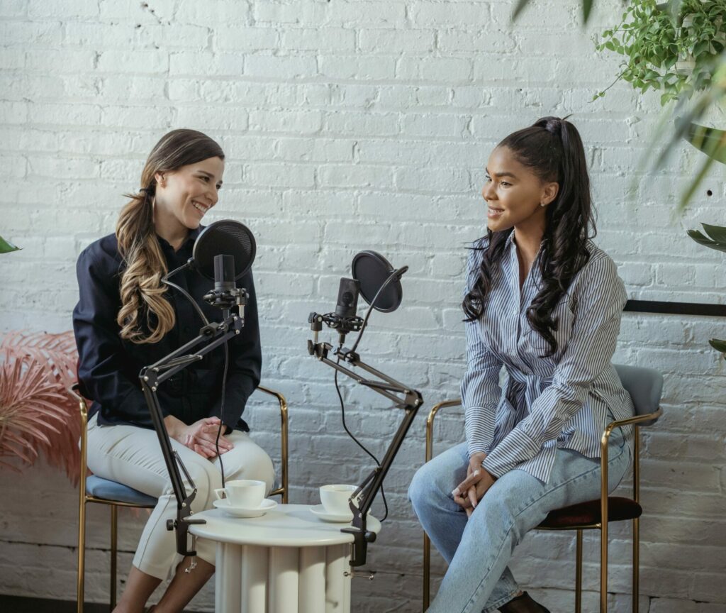 Diverse women communicating while recording voice in studio with white brick walls in daytime